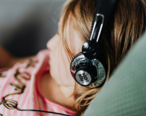 a close up of a child wearing headphones laying down on a sofa wearing a pink tshirt